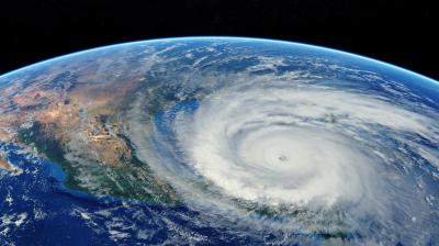 Satellite view of a large, swirling hurricane over the ocean near a continent, with a clear eye at the center and surrounding cloud bands.