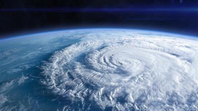 Satellite view of a swirling cyclone over the ocean with curved white clouds and deep blue water beneath.