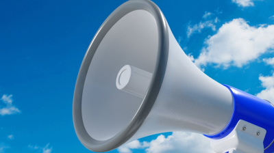 Close-up of a blue and white megaphone facing left against a clear sky with scattered clouds.