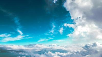 A view of the sky with white and grey clouds under a blue sky, seen from above or within the clouds.