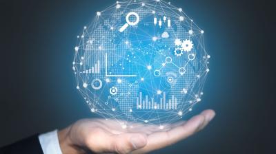 A hand holds a digital globe with interconnected icons and graphs representing data analytics, technology, and global connectivity on a blue background.