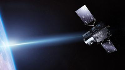 A satellite with solar panels orbits Earth in space, with the planet’s blue surface and a bright light visible on the left side.