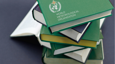 A stack of hardcover books, with the top book titled "World Meteorological Organization" and bearing its logo, set against a dark background.