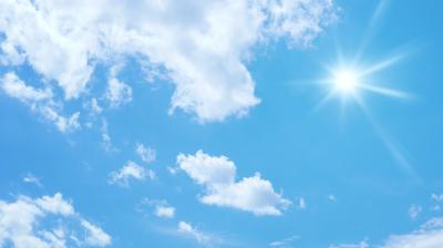 Blue sky with scattered white clouds and the sun shining brightly in the upper right corner.