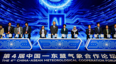 A group of officials stands behind podiums on stage at the 4th China-ASEAN Meteorological Cooperation Forum with a digital AI-themed backdrop.