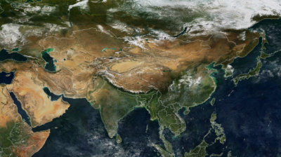 Satellite view of Asia showing diverse landscapes including deserts, mountains, forests, and bodies of water, with snow covering the northern regions.
