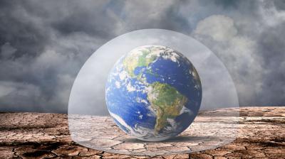 A glass dome encloses a globe showing the Americas, set on cracked, dry ground under a cloudy sky.