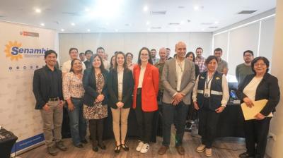 A group of people pose for a photo in a conference room, standing in front of a Senamhi banner and a projection screen.
