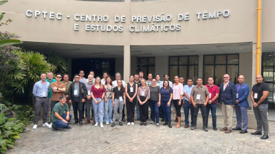 A group of people poses for a photo in front of the CPTEC - Centro de Previsão de Tempo e Estudos Climáticos building.