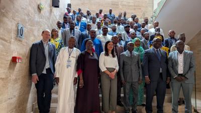 A large group of people in formal attire pose for a photo on a staircase inside a modern building.