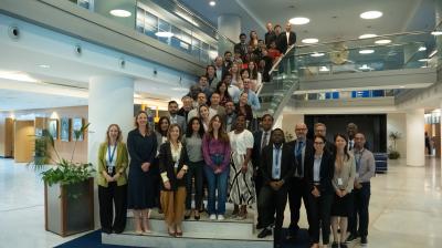 A large group of people posing for a photo on the stairs of a modern office building lobby.
