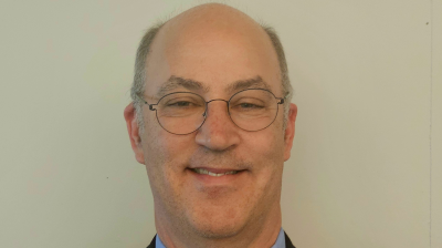 Headshot of Brian Cover with glasses smiling against a plain background.
