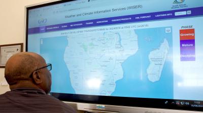 A person looking at a large computer screen displaying a South African Weather Service map of thunderstorms across Southern Africa.