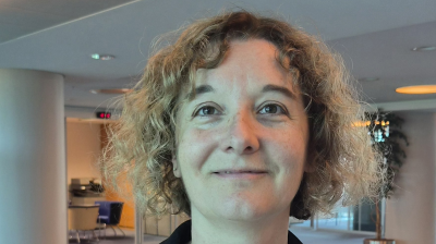 A woman with curly shoulder-length hair looking toward the camera.