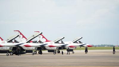 Four F-16 Fighting Falcon aircraft from the USAF Thunderbirds parked on a flight line with crew members standing nearby.