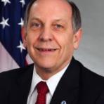 A man in a suit and tie in front of an american flag.