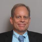 A man in a suit and tie smiles for the camera.