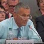 A man sitting at a table in front of a group of people.
