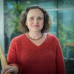 A woman in a red sweater standing next to a railing.