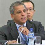 A man in a suit and tie is speaking at a meeting.
