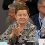 A woman clapping at a conference table.