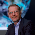 A man in glasses sitting in front of a globe.