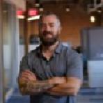 A man with a beard standing in an office.