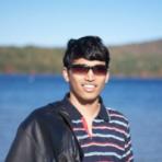 A man in sunglasses standing in front of a body of water.