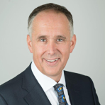 A man in a suit and tie smiling for the camera.