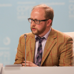 A man sitting at a table with a microphone.