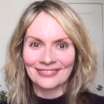 A woman is smiling in front of a camera.