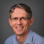 A man wearing glasses and a blue shirt.