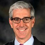 A man in glasses wearing a suit and tie.