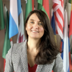 A woman standing in front of a wall of flags.