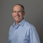 A man in a blue shirt smiling for the camera.