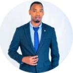 A man in a blue suit with a matching tie poses against a white background, facing the camera.