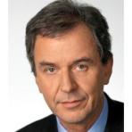 A man with short, dark hair and a suit jacket, looking directly at the camera with a neutral expression.