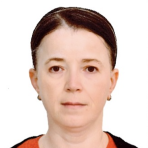 A woman with fair skin and dark brown hair pulled back, wearing small hoop earrings, a red top, and a black sweater, facing the camera against a plain white background.