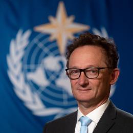 Cyrille Honoré standing in front of WMO flag.