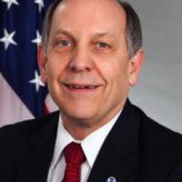 A man in a suit and tie in front of an american flag.