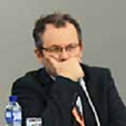A man sitting at a table with his hand on his face.