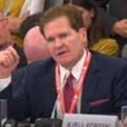 A man in a suit and tie is sitting at a table.
