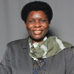 A woman in a suit and a scarf smiling.