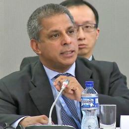 A man in a suit and tie is speaking at a meeting.