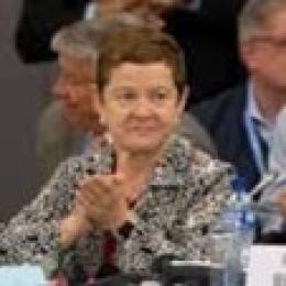 A woman clapping at a conference table.