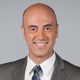 A bald man in a suit and tie smiling.