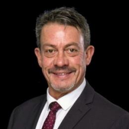 A man in a suit and tie smiling for the camera.