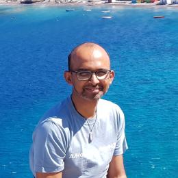 A man standing on a ledge in front of a body of water.