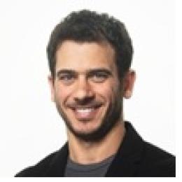 A man smiling in front of a white background.