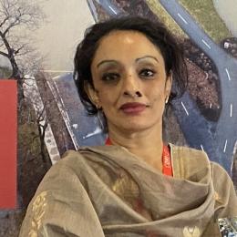 A woman in a sari standing in front of a poster.